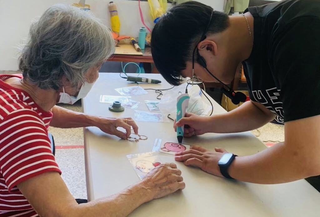 Yu-Hsuan Liao (right) from the “Sweet Potato Ball Volunteer Team” leads the group into Mingjian Township, Nantou, teaching seniors how to use 3D printing pens to create fun models - bringing emerging technology to the community and inspiring hands-on creativity for all ages.