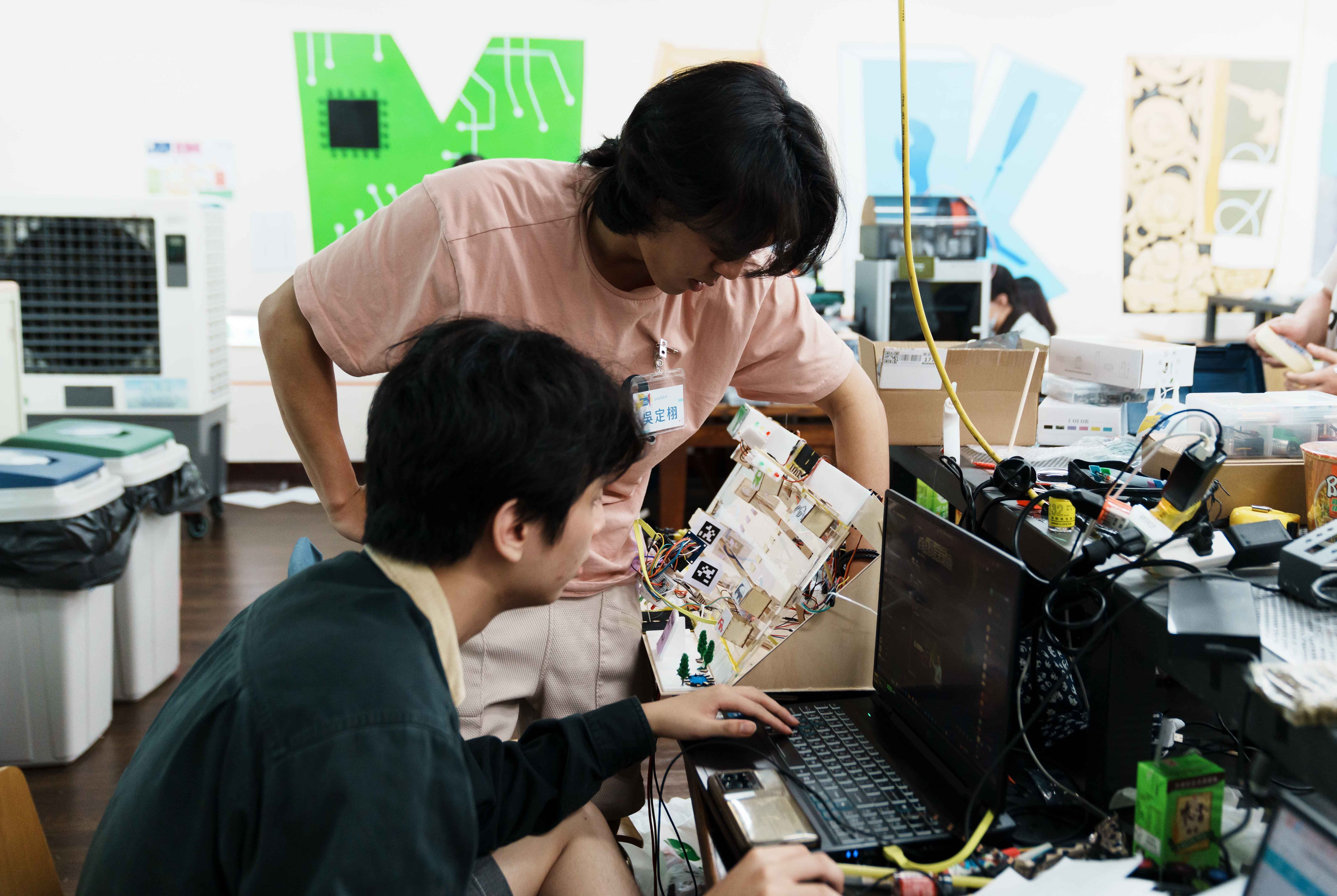 Ting-Hsu Wu (back) and Ping-Cheng Hsieh (front) were primarily responsible for training the visual recognition model and developing the analytics platform, enabling the system to detect traffic flow and adjust signal timing - helping to ease congestion, reduce idling, and lower carbon emissions. Photo courtesy of the event organizers.